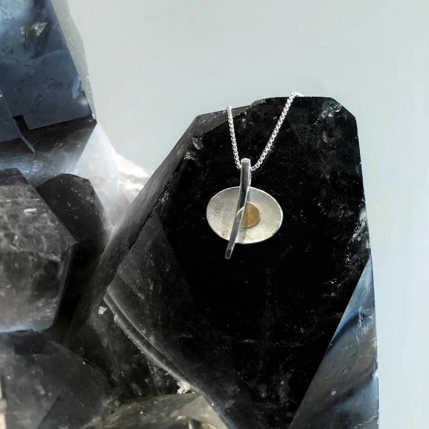 Photo of Pierced Oval Pendant in a decorative scene, designed by , available at Plumb Gold & Plumb Silver