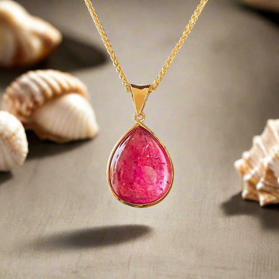 Photo of Pink Tourmaline Cabochon Pendant in a decorative scene, designed by , available at Plumb Gold & Plumb Silver