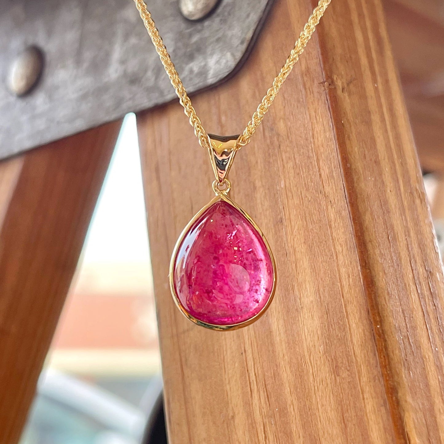 Photo of Pink Tourmaline Cabochon Pendant in a decorative scene, designed by , available at Plumb Gold & Plumb Silver