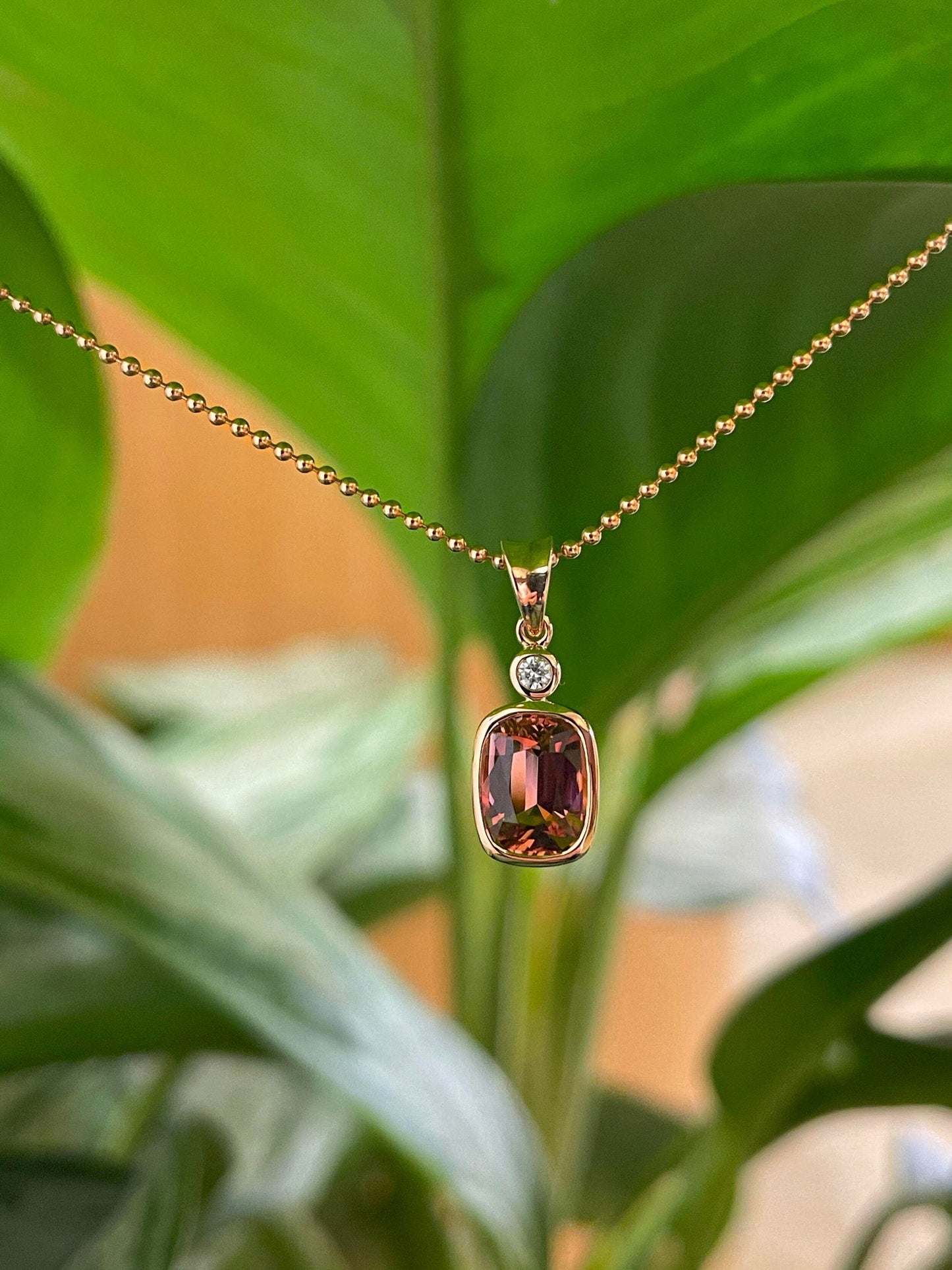 Photo of Pink Tourmaline and Diamond Pendant in a decorative scene, designed by , available at Plumb Gold & Plumb Silver