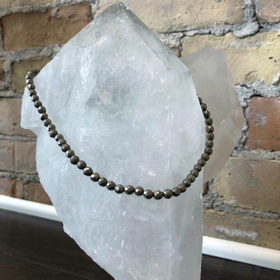 Photo of Pyrite Bead Necklace in a decorative scene, designed by , available at Plumb Gold & Plumb Silver
