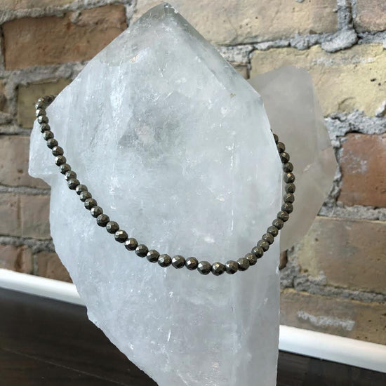Photo of Pyrite Bead Necklace in a decorative scene, designed by , available at Plumb Gold & Plumb Silver