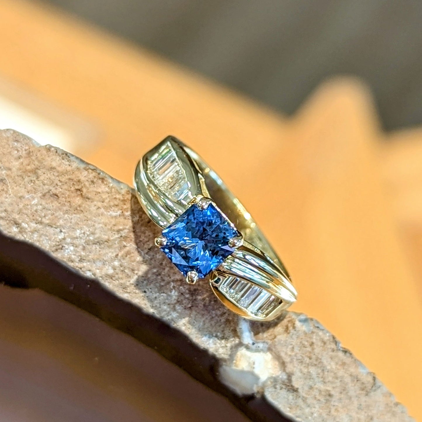 Photo of Radiant Sapphire and Baguette Ring in a decorative scene, designed by , available at Plumb Gold & Plumb Silver