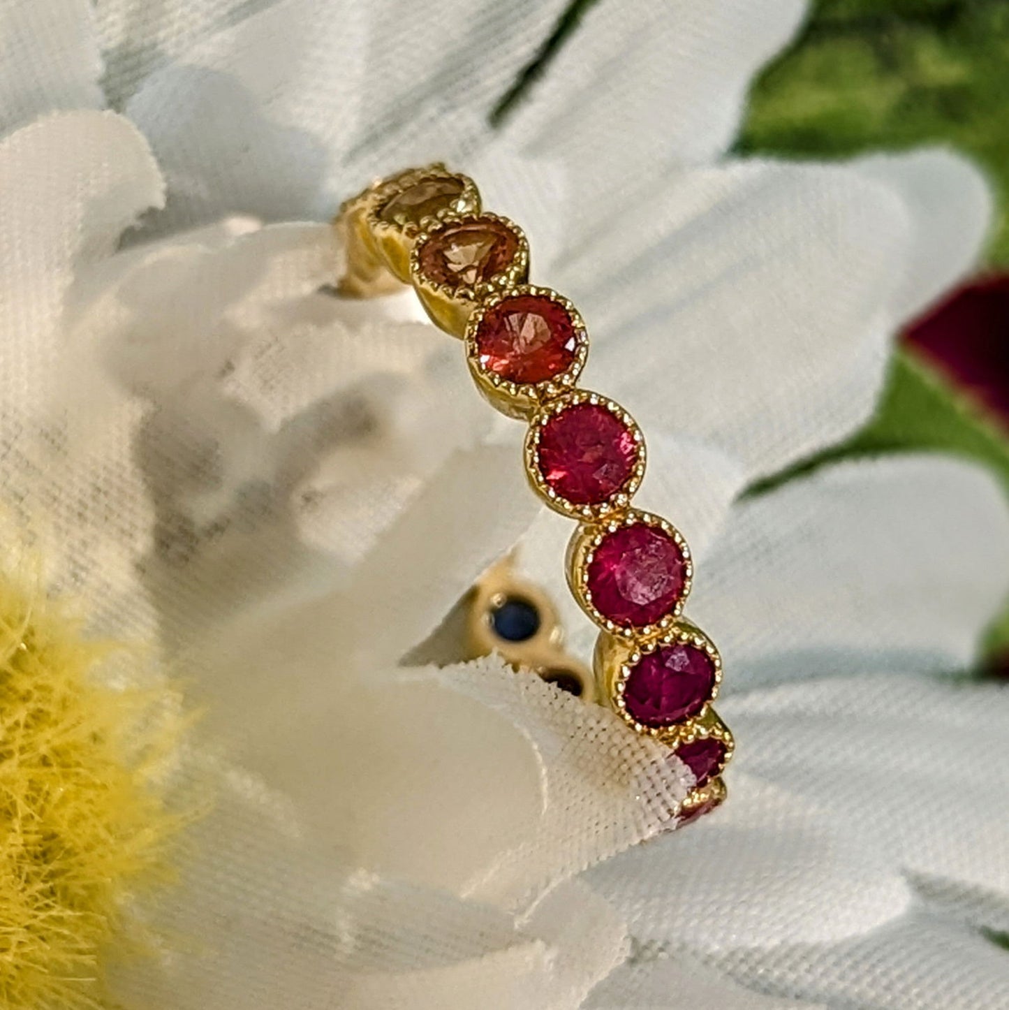 Photo of Rainbow Sapphire Eternity Band in a decorative scene, designed by , available at Plumb Gold & Plumb Silver