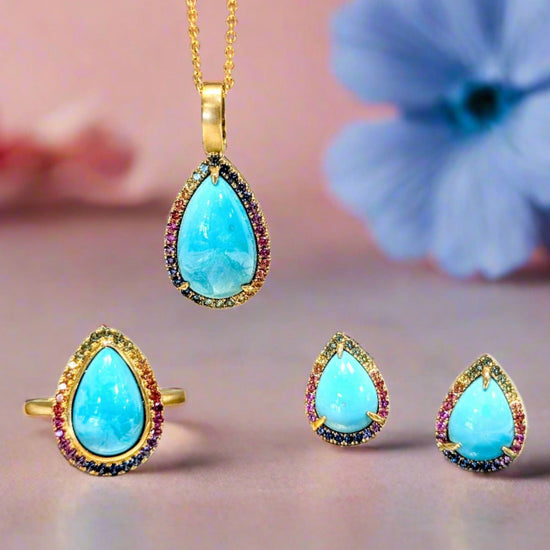 Photo of Rainbow Sapphire Halo Turquoise Pendant in a decorative scene, designed by , available at Plumb Gold & Plumb Silver