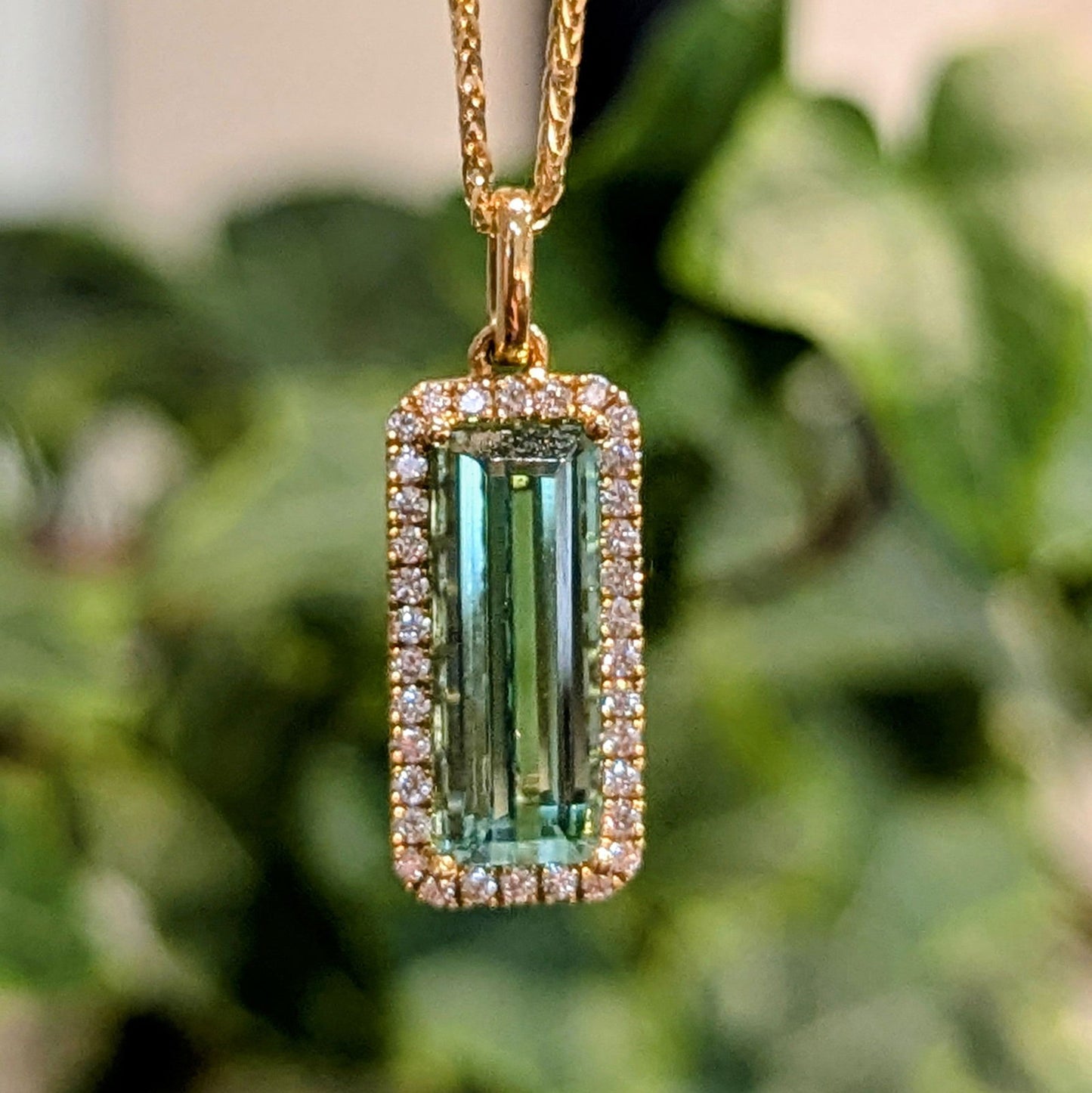 Photo of Rectangle Tourmaline Halo Pendant in a decorative scene, designed by , available at Plumb Gold & Plumb Silver