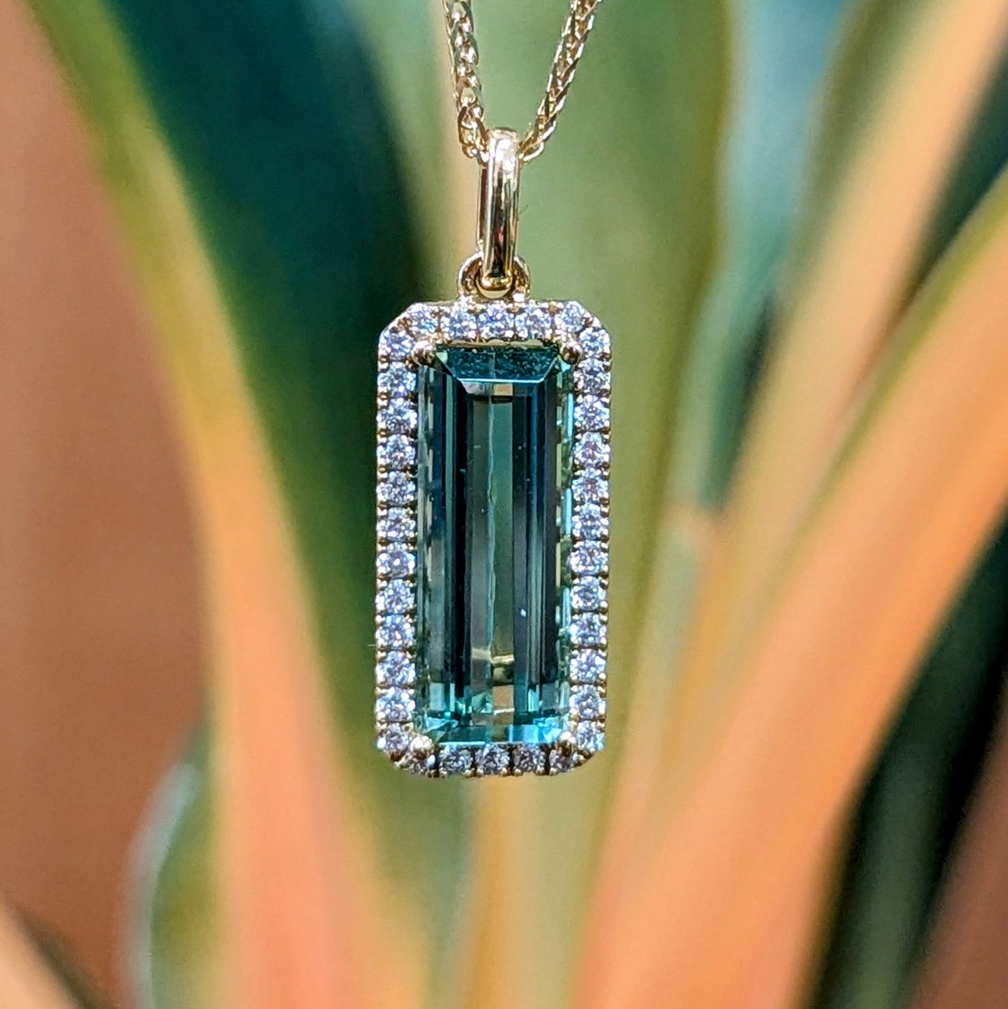 Photo of Rectangle Tourmaline Halo Pendant in a decorative scene, designed by , available at Plumb Gold & Plumb Silver