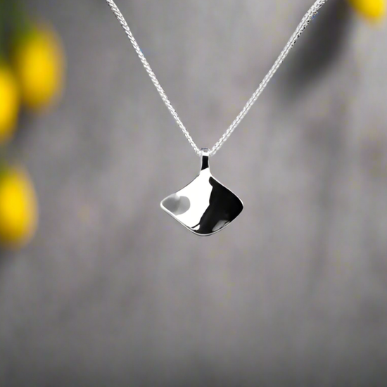 Photo of "Reflection" Necklace in a decorative scene, designed by , available at Plumb Gold & Plumb Silver