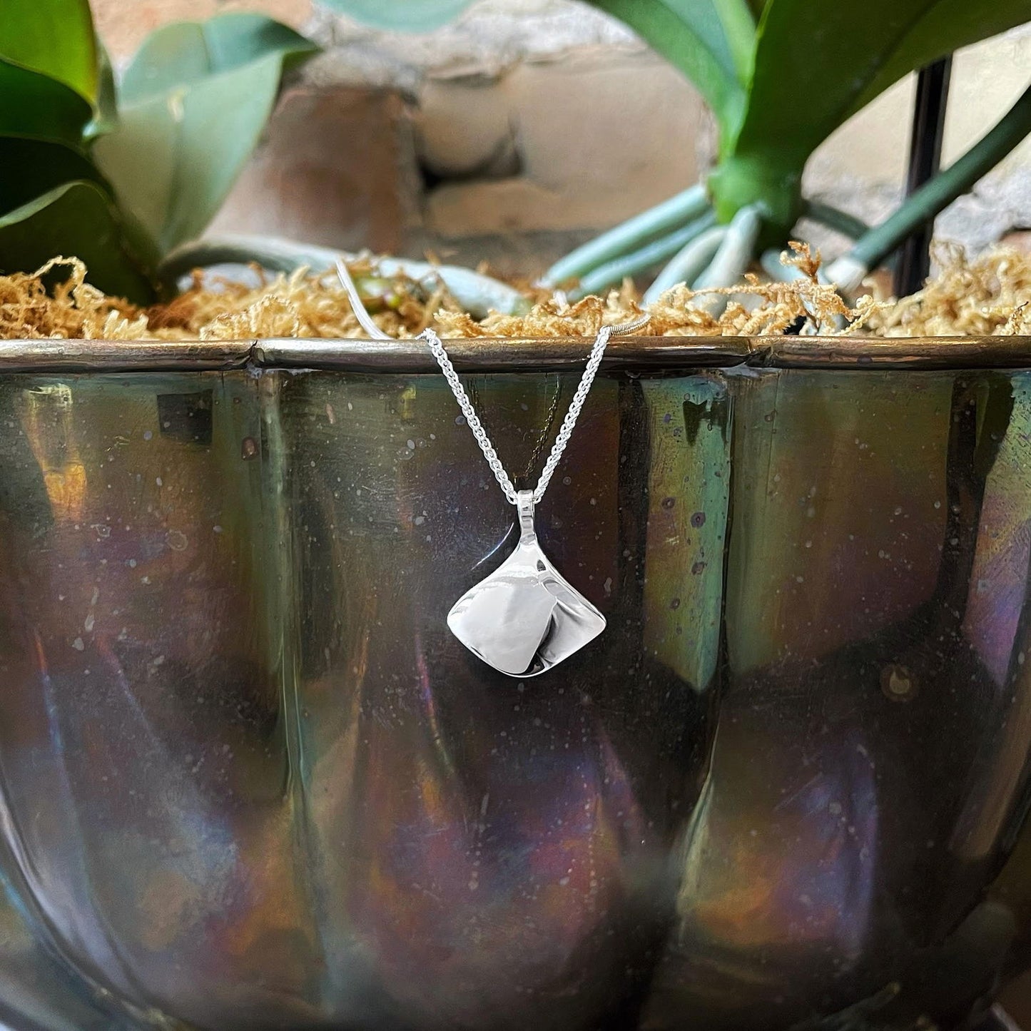 Photo of "Reflection" Necklace in a decorative scene, designed by , available at Plumb Gold & Plumb Silver