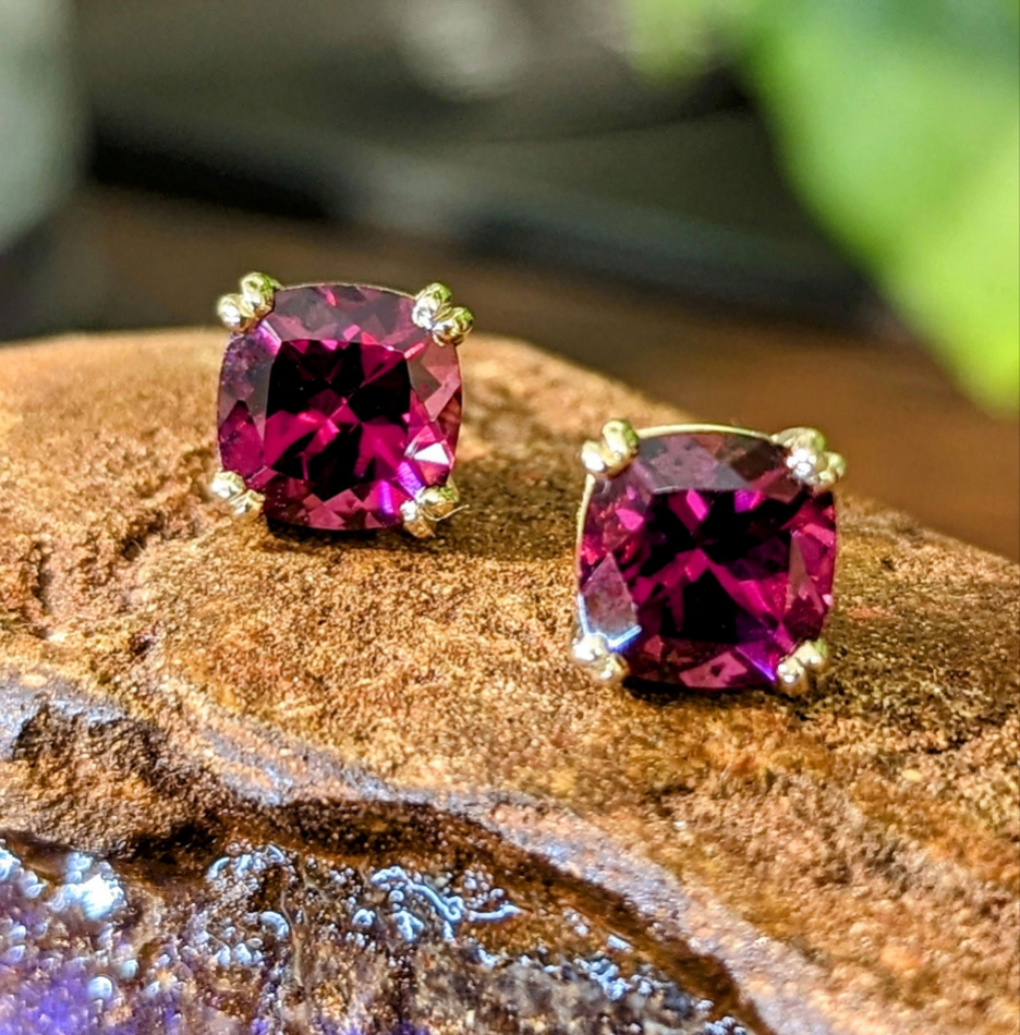 Photo of Rhodolite Garnet studs in a decorative scene, designed by -, available at Plumb Gold & Plumb Silver