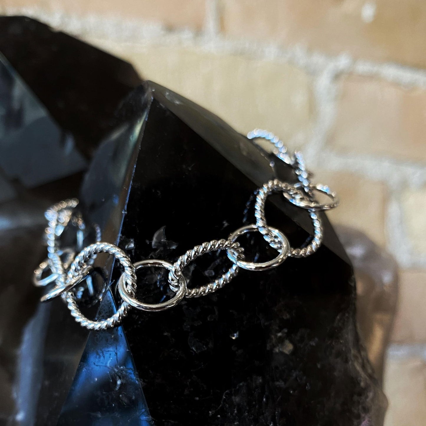 Photo of Rope Circle and Ovals Link Bracelet in a decorative scene, designed by , available at Plumb Gold & Plumb Silver