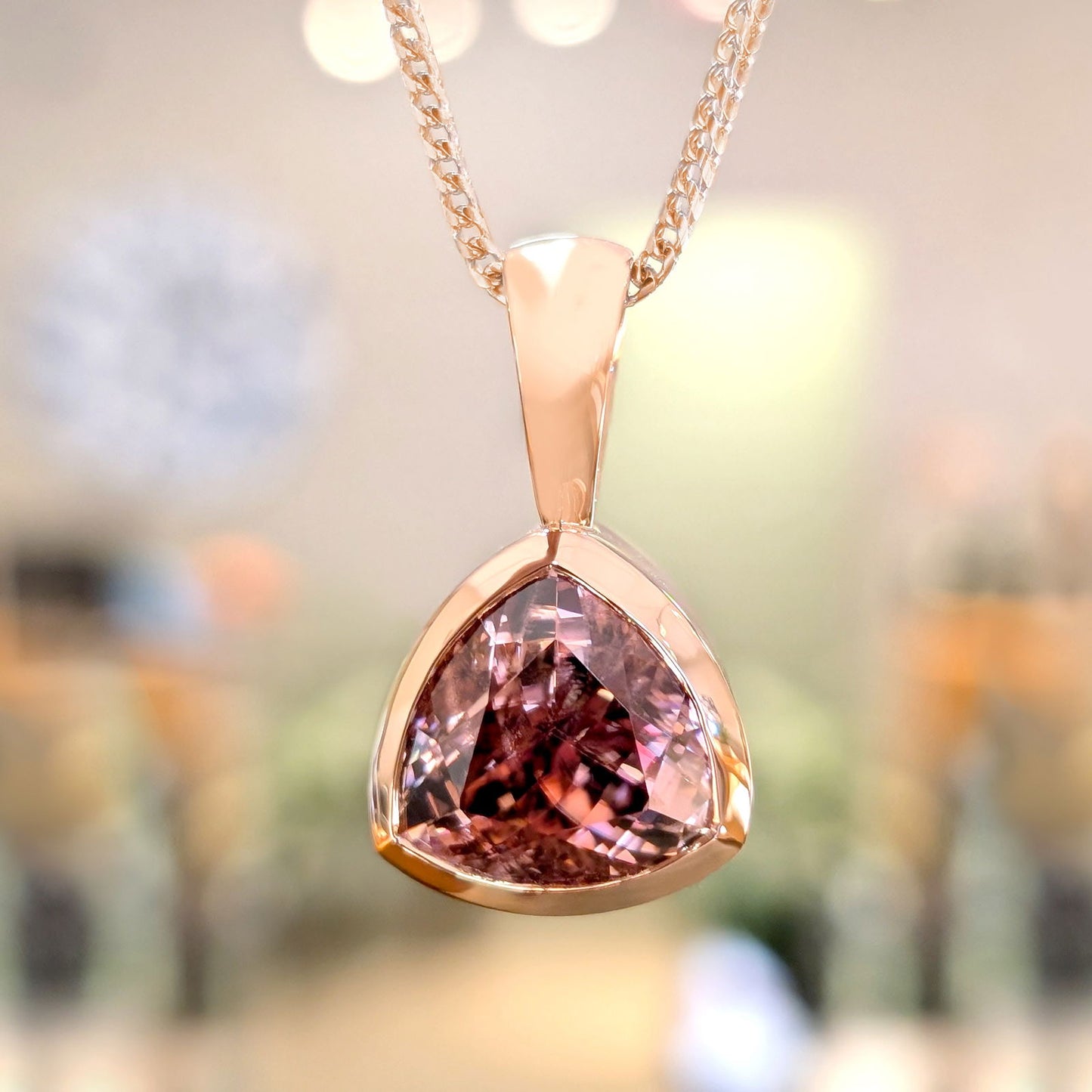 Photo of Rose Zircon Trilliant Pendant in a decorative scene, designed by , available at Plumb Gold & Plumb Silver