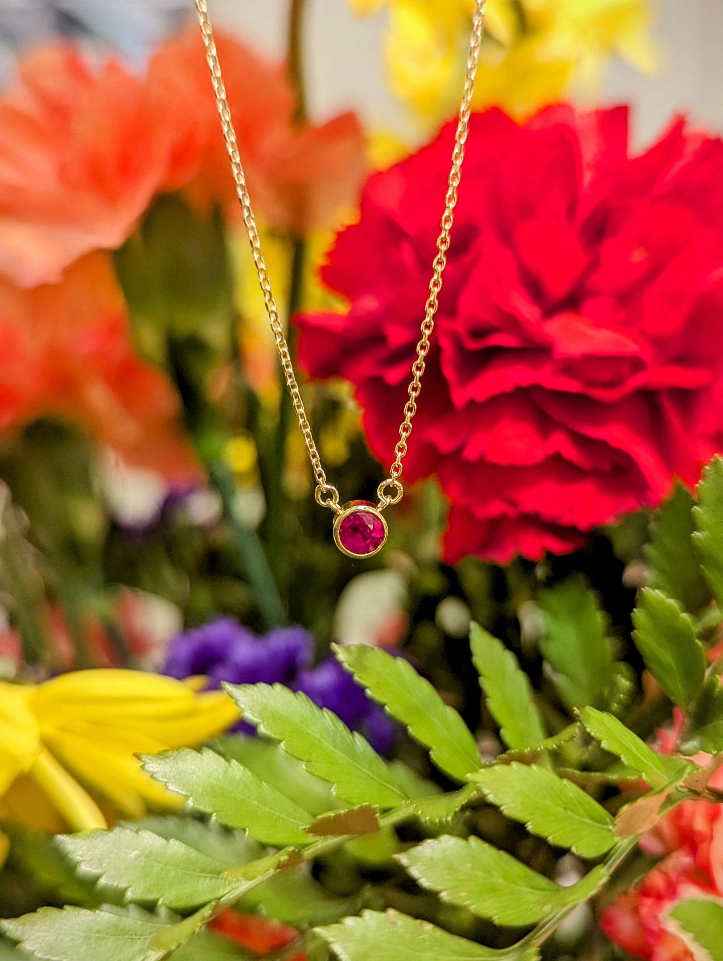 Photo of Ruby Bezel Necklace in a decorative scene, designed by , available at Plumb Gold & Plumb Silver