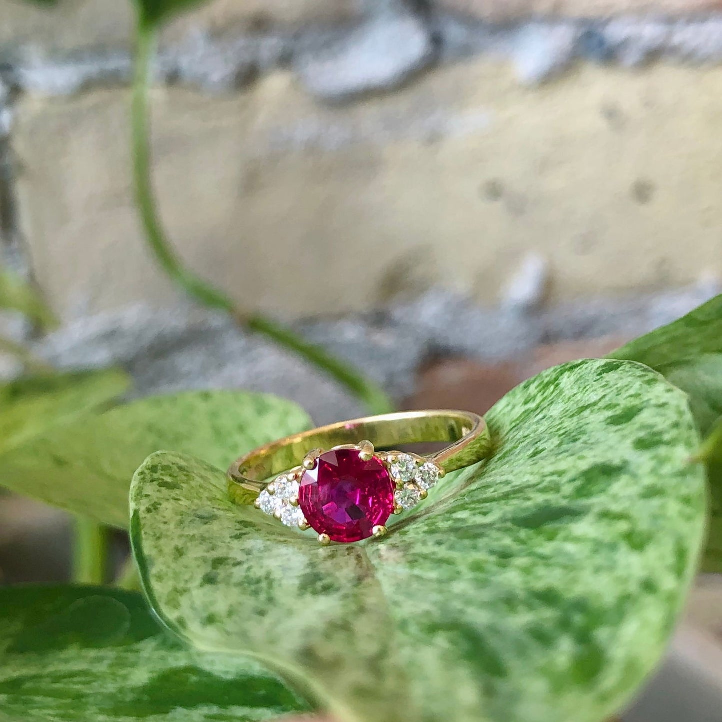 Photo of Ruby Ring with Diamond Trio Accents in a decorative scene, designed by , available at Plumb Gold & Plumb Silver
