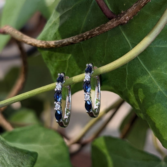 Photo of Sapphire and Diamond Hinged Hoop Earrings in a decorative scene, designed by , available at Plumb Gold & Plumb Silver