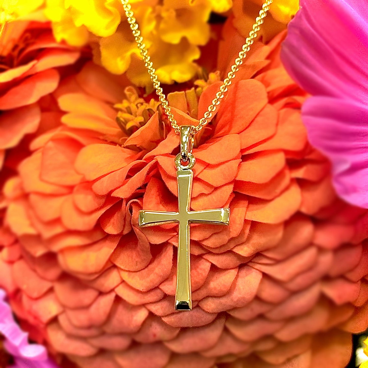 Photo of Simple Tapered Cross Pendant in a decorative scene, designed by , available at Plumb Gold & Plumb Silver