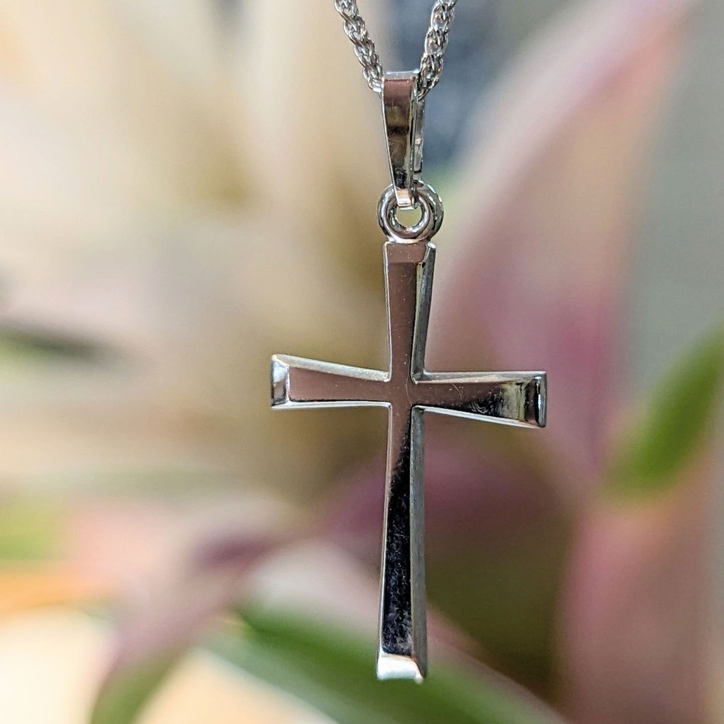 Photo of Simple Tapered Cross Pendant in a decorative scene, designed by , available at Plumb Gold & Plumb Silver