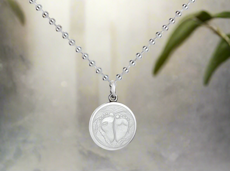 Photo of Small Baby Feet Pendant in a decorative scene, designed by , available at Plumb Gold & Plumb Silver