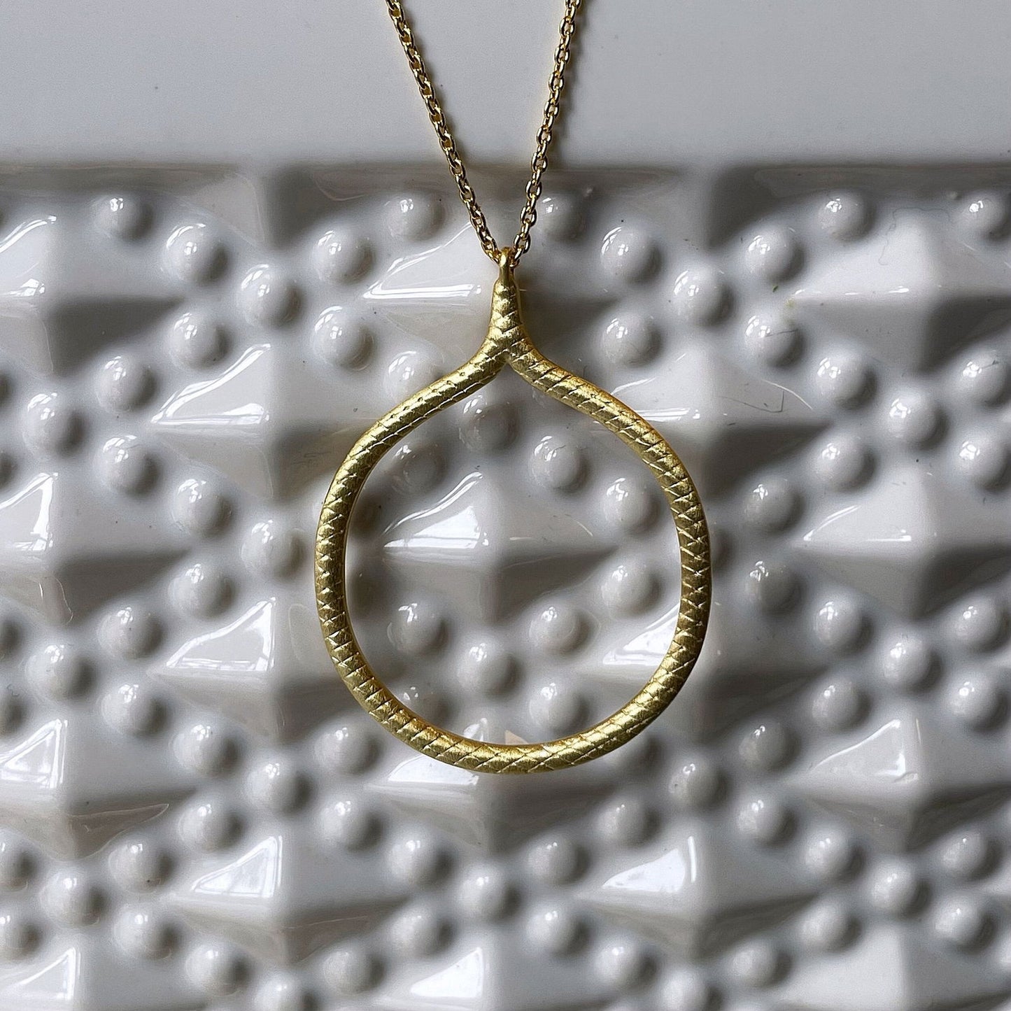 Photo of “Snakeskin” Pendant in a decorative scene, designed by , available at Plumb Gold & Plumb Silver