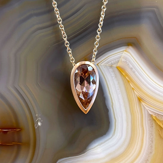 Photo of Spice Zircon Necklace in a decorative scene, designed by , available at Plumb Gold & Plumb Silver