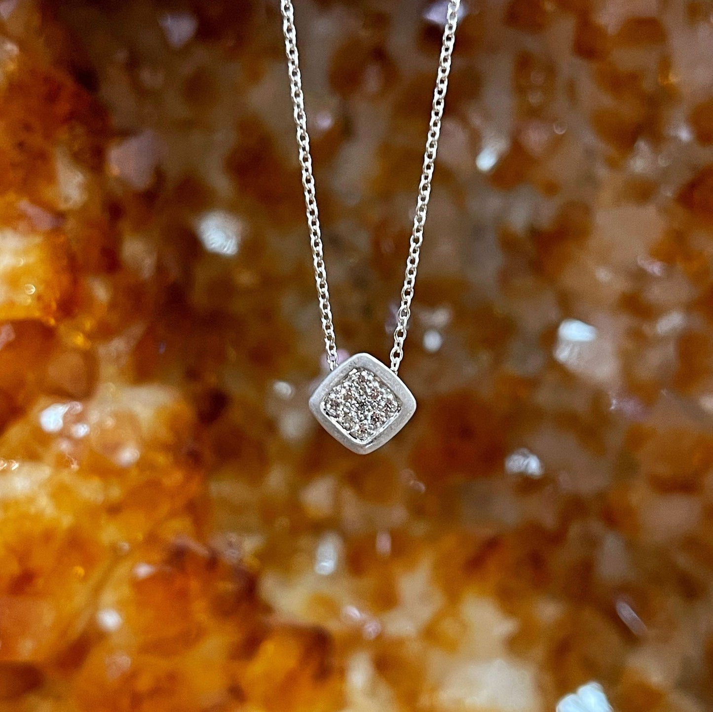 Photo of Square Frame Cluster necklace in a decorative scene, designed by , available at Plumb Gold & Plumb Silver