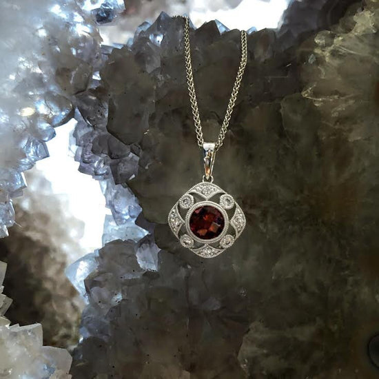 Photo of Stanton Color Vintage-Inspired Rhodolite Garnet Pendant in a decorative scene, designed by , available at Plumb Gold & Plumb Silver