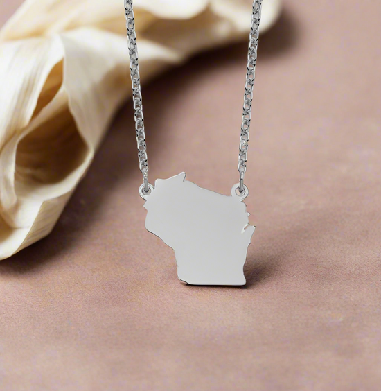 Photo of Sterling Silver Wisconsin Necklace in a decorative scene, designed by , available at Plumb Gold & Plumb Silver