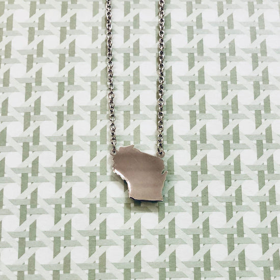 Photo of Sterling Silver Wisconsin Necklace in a decorative scene, designed by , available at Plumb Gold & Plumb Silver