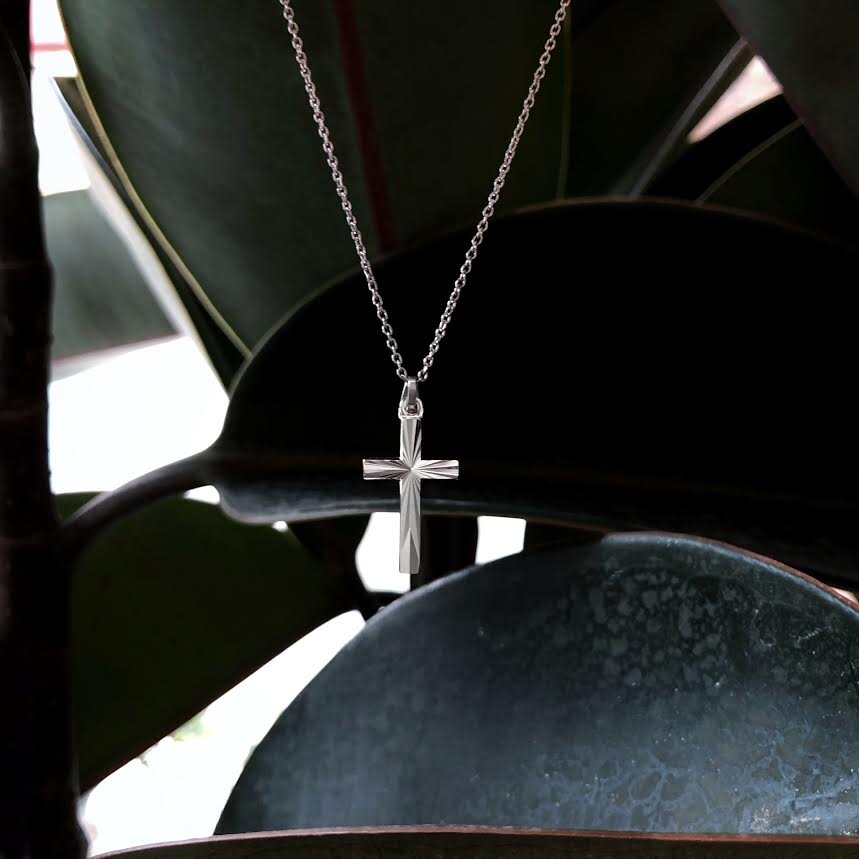 Cross hanging in front of Green leaf