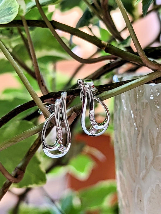 Photo of Swoop Diamond Accented Post Earrings in a decorative scene, designed by , available at Plumb Gold & Plumb Silver