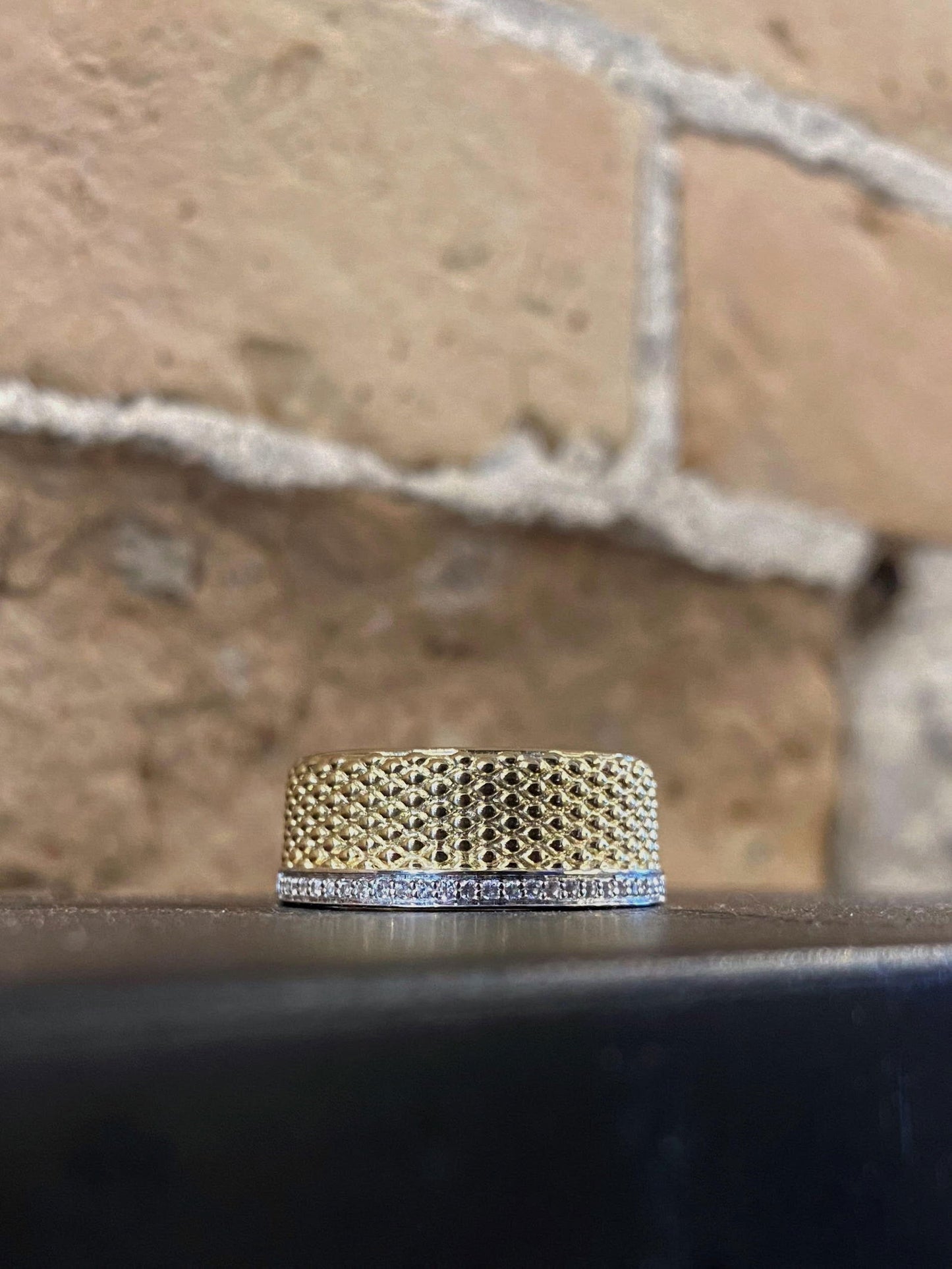 Photo of Textured Two-Tone Ring with White Sapphire Accents in a decorative scene, designed by , available at Plumb Gold & Plumb Silver