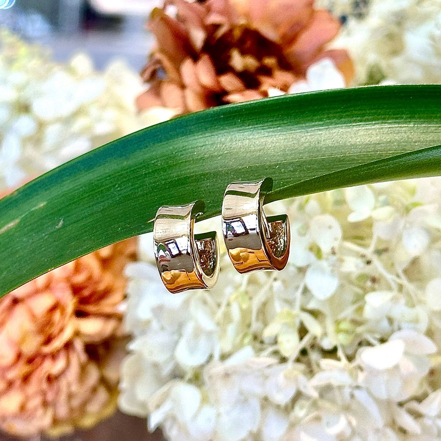 Photo of Thick Bowed Huggie in a decorative scene, designed by -, available at Plumb Gold & Plumb Silver