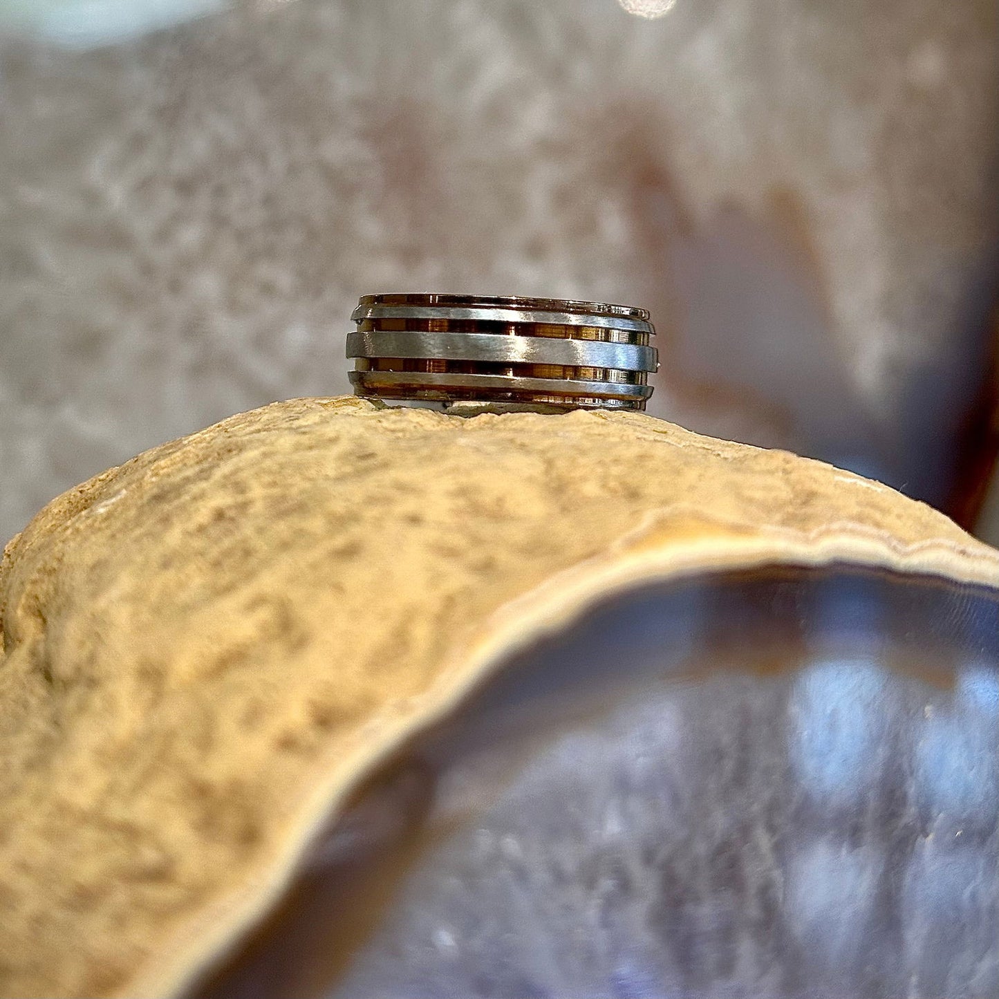 Photo of Titanium Bronzed Step Edge Grooved Band in a decorative scene, designed by , available at Plumb Gold & Plumb Silver