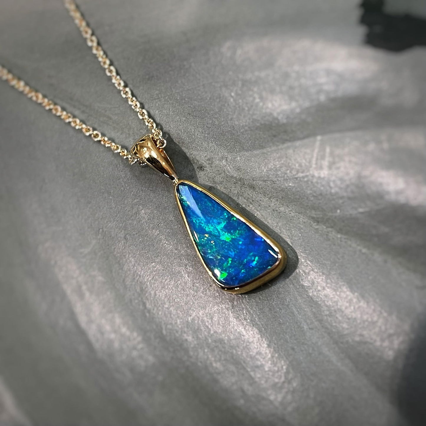 Photo of Triangular Opal Pendant in a decorative scene, designed by , available at Plumb Gold & Plumb Silver