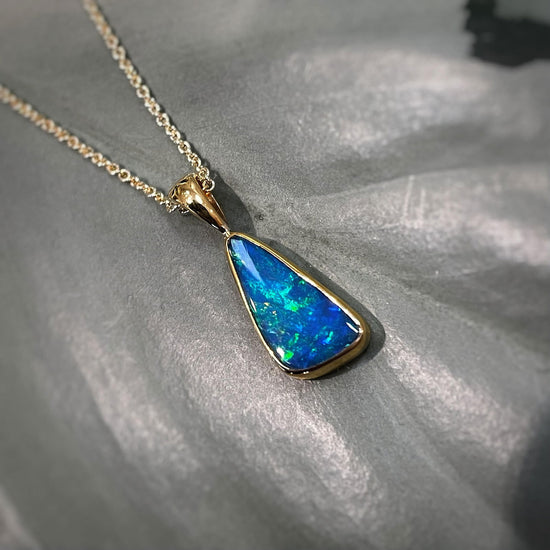Photo of Triangular Opal Pendant in a decorative scene, designed by , available at Plumb Gold & Plumb Silver