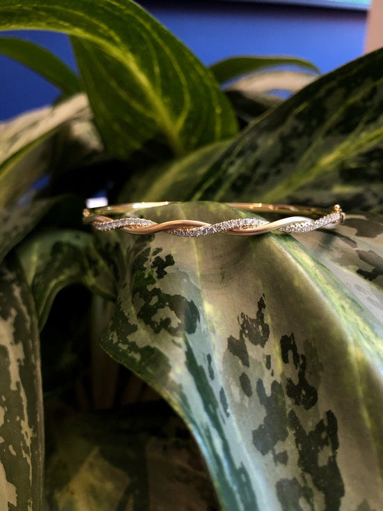 Photo of Twist Bangle Bracelet in a decorative scene, designed by , available at Plumb Gold & Plumb Silver