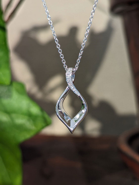 Photo of Twist Pendant with Diamond Accent in a decorative scene, designed by , available at Plumb Gold & Plumb Silver