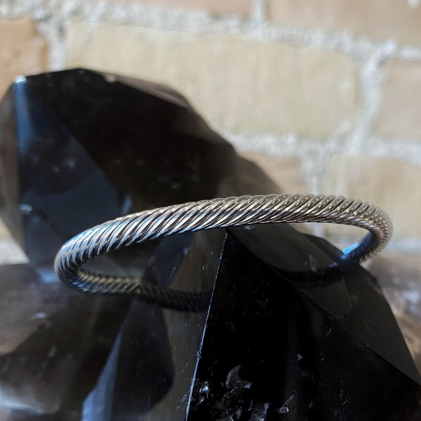 Photo of Twisted Cuff Bracelet in a decorative scene, designed by , available at Plumb Gold & Plumb Silver