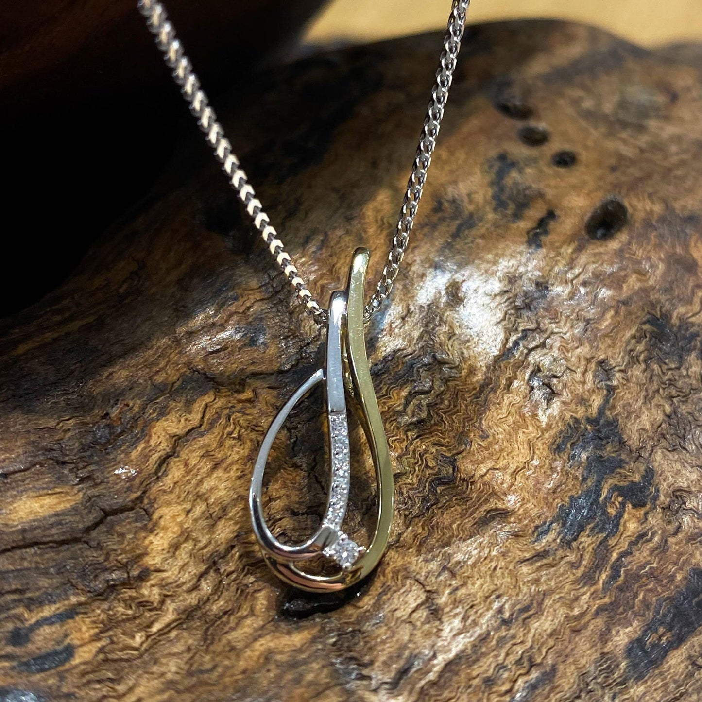 Photo of Two-Tone Teardrop Pendant with Diamond Accents in a decorative scene, designed by , available at Plumb Gold & Plumb Silver