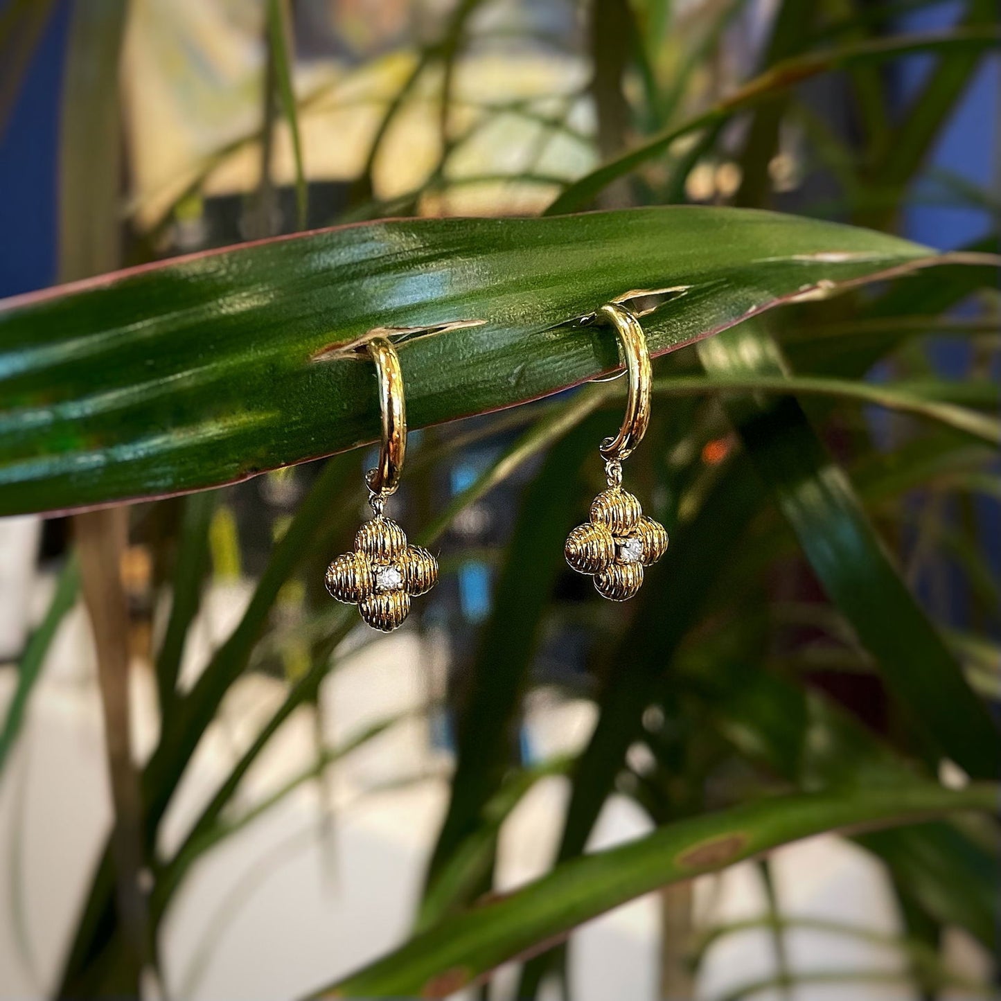 Photo of White Sapphire Clover Dangles in a decorative scene, designed by , available at Plumb Gold & Plumb Silver