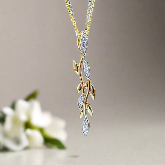 Photo of White Sapphire Vine Pendant in a decorative scene, designed by , available at Plumb Gold & Plumb Silver