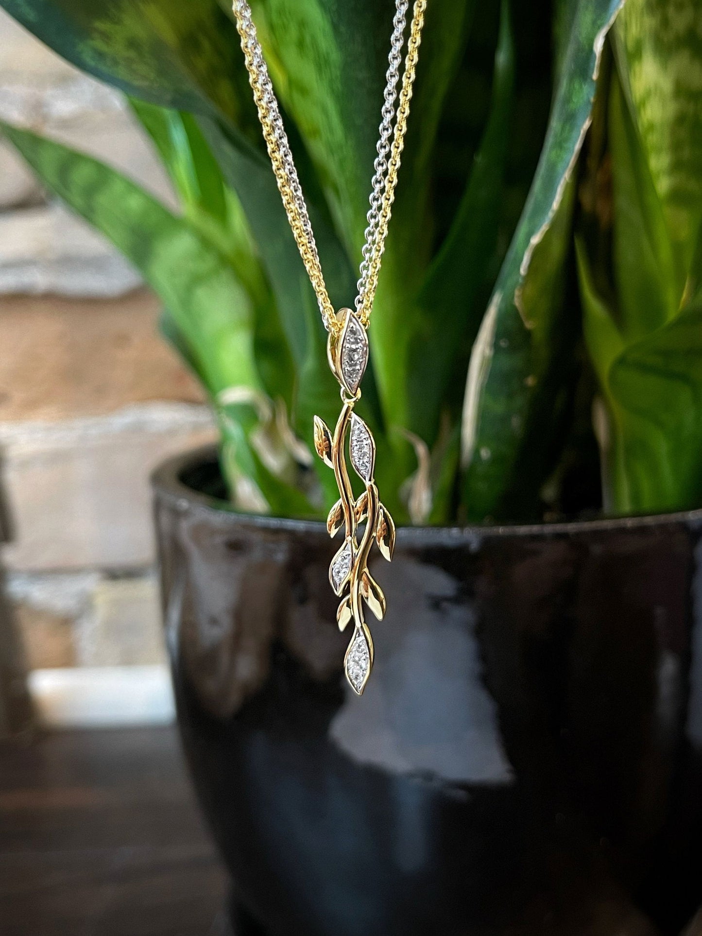 Photo of White Sapphire Vine Pendant in a decorative scene, designed by , available at Plumb Gold & Plumb Silver