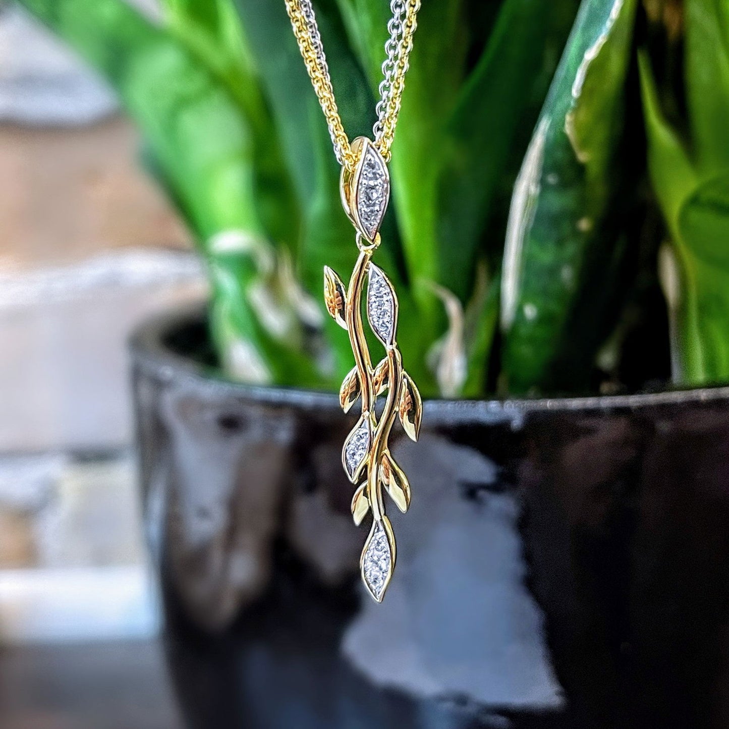 Photo of White Sapphire Vine Pendant in a decorative scene, designed by , available at Plumb Gold & Plumb Silver