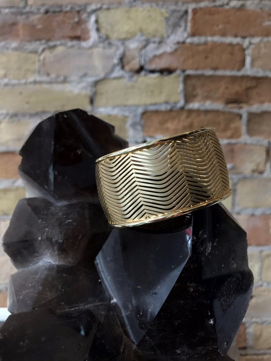 Photo of Wide Herringbone Cuff in a decorative scene, designed by , available at Plumb Gold & Plumb Silver