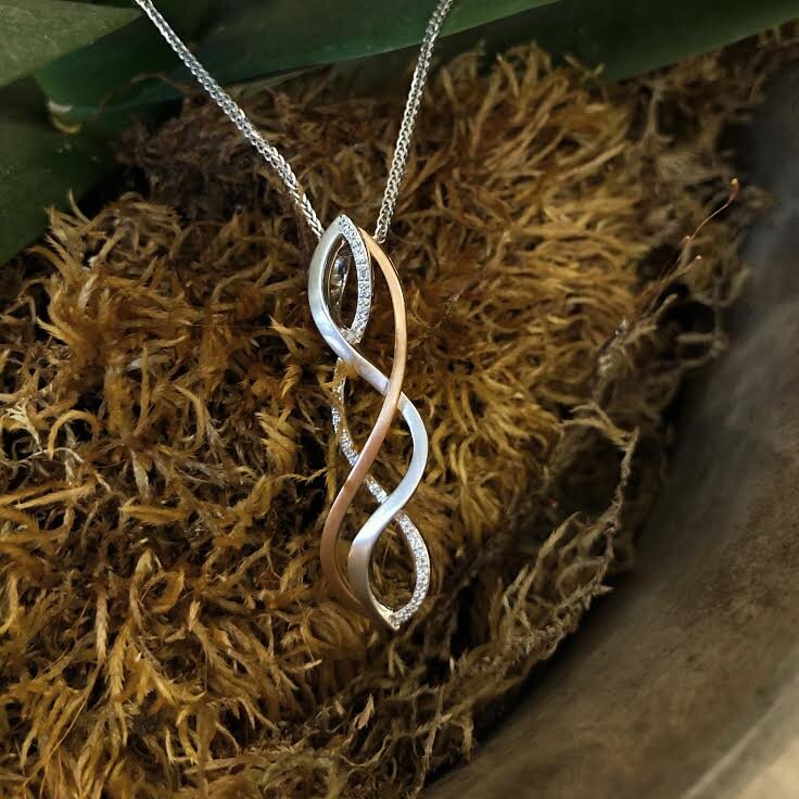 Photo of Woven Twist Diamond Pendant in a decorative scene, designed by , available at Plumb Gold & Plumb Silver