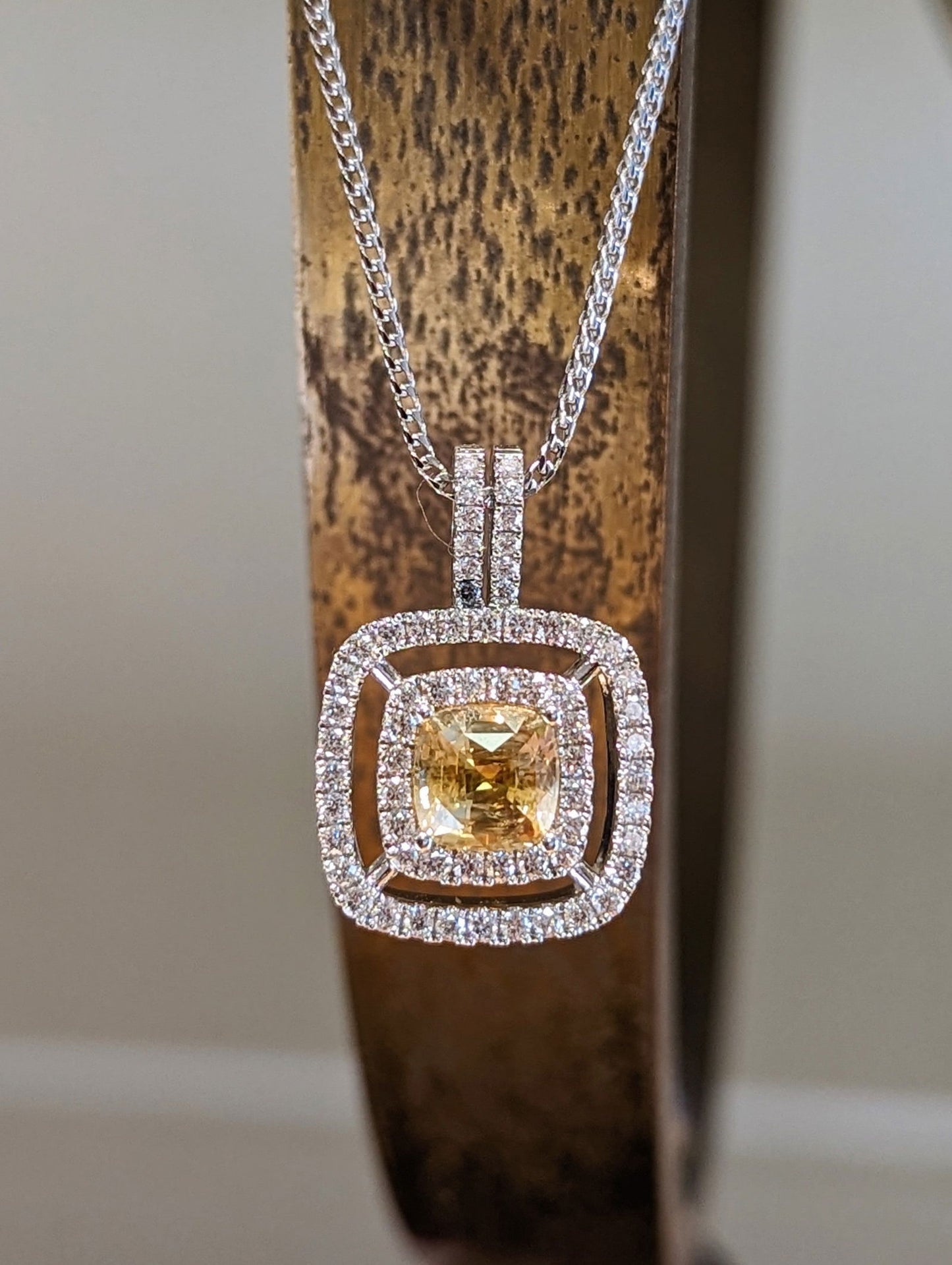 Photo of Yellow Sapphire Diamond Halo Pendant in a decorative scene, designed by , available at Plumb Gold & Plumb Silver