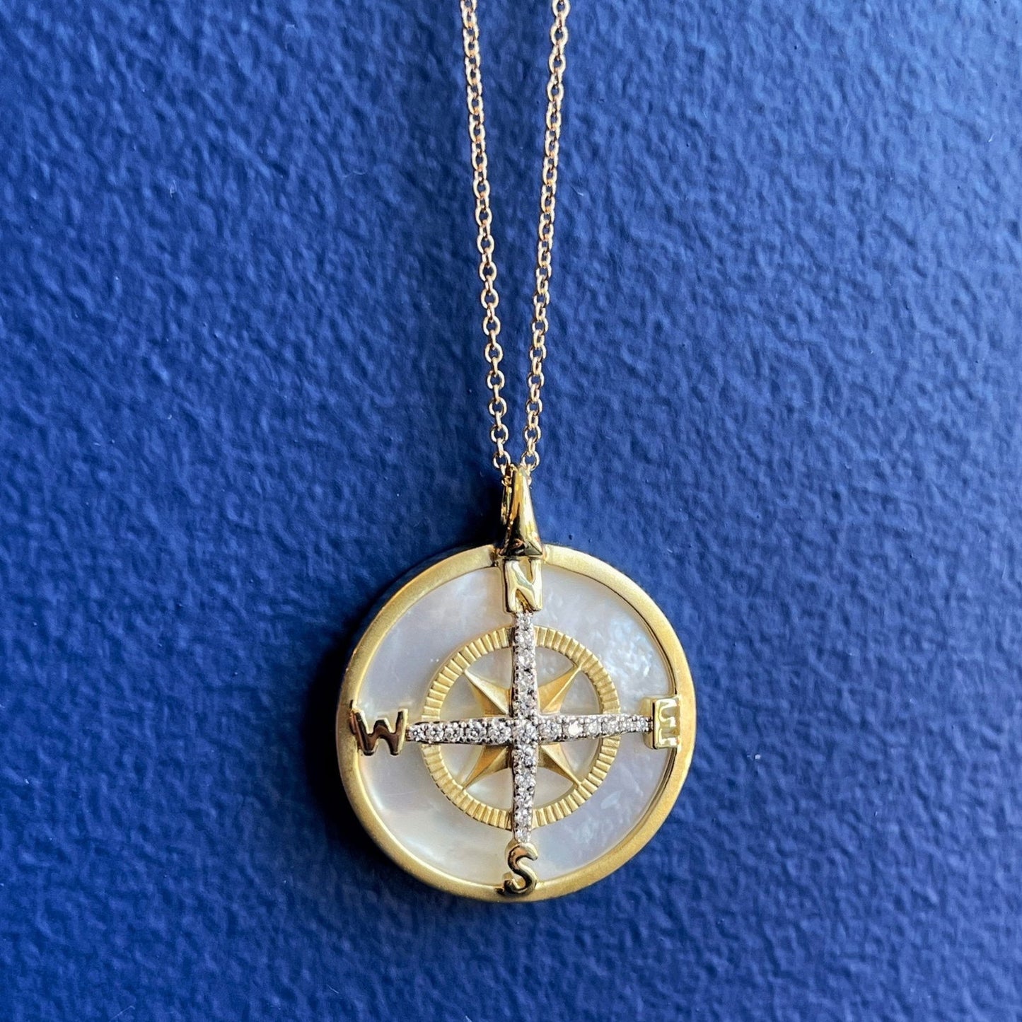 Photo of Zeghani Mother of Pearl and Diamond Compass Necklace in a decorative scene, designed by , available at Plumb Gold & Plumb Silver