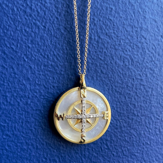 Photo of Zeghani Mother of Pearl and Diamond Compass Necklace in a decorative scene, designed by , available at Plumb Gold & Plumb Silver