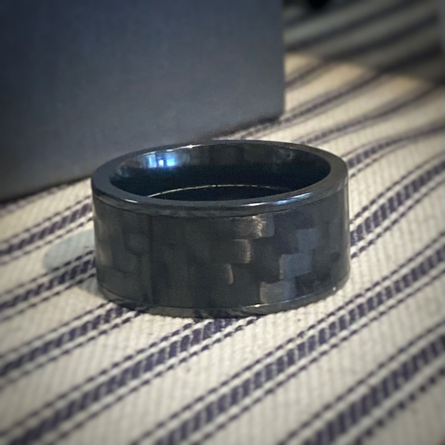 Photo of Zirconium Carbon Fiber Wide Band in a decorative scene, designed by , available at Plumb Gold & Plumb Silver