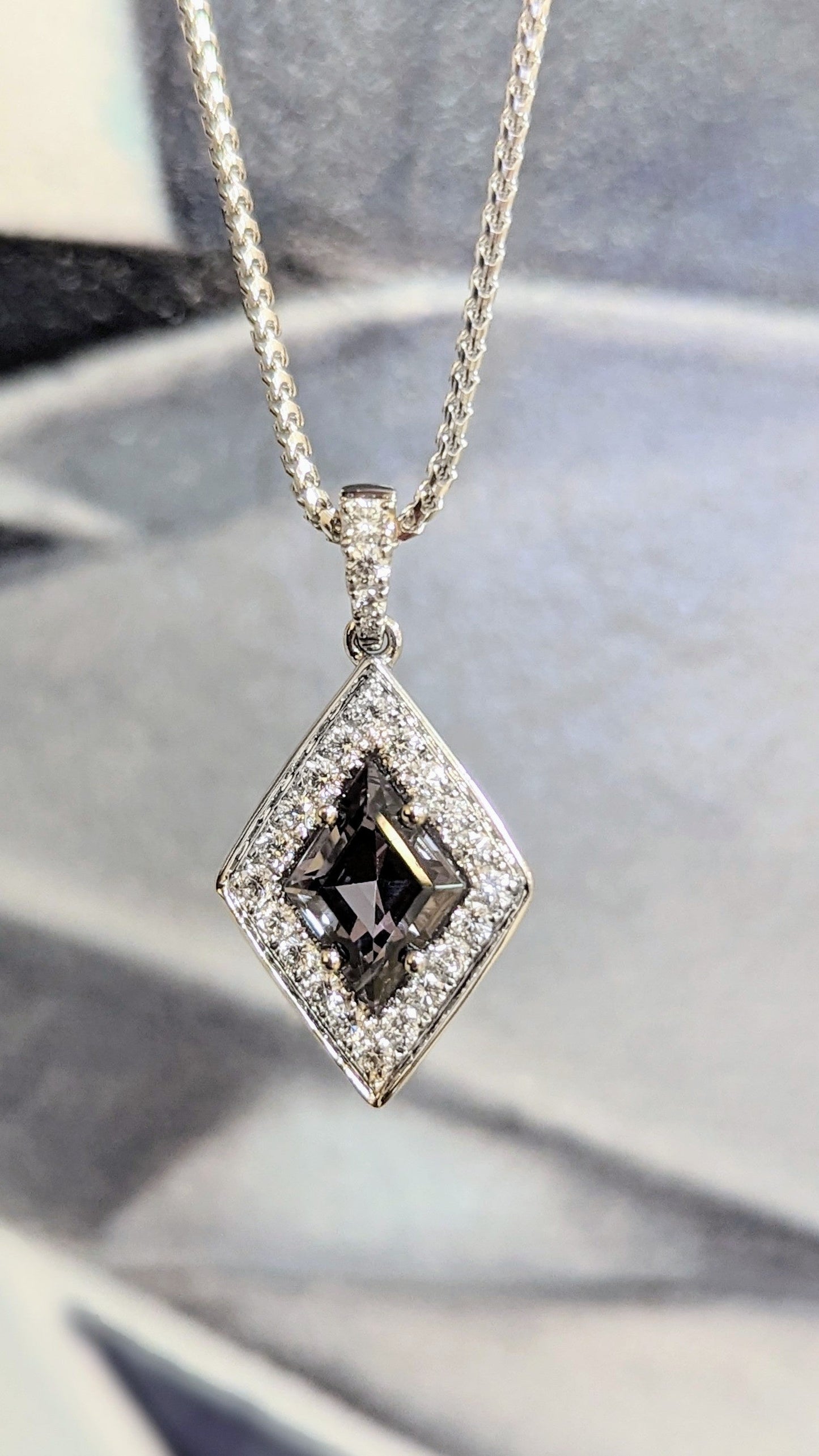 Photo of Zoma Color Grey Spinel Pendant in a decorative scene, designed by , available at Plumb Gold & Plumb Silver